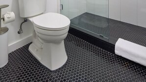 Une salle de bain moderne équipée de toilettes, d’une douche à parois de verre et d’un porte-serviettes en métal.