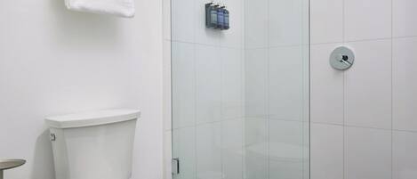 A modern bathroom with a toilet, a glass shower enclosure, and a metal towel rack.