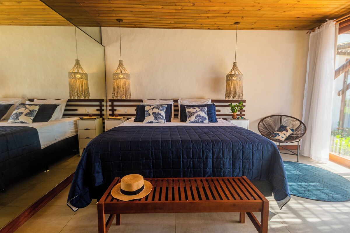 A bedroom with a large bed, two bedside tables, a wooden bench, and a chair.