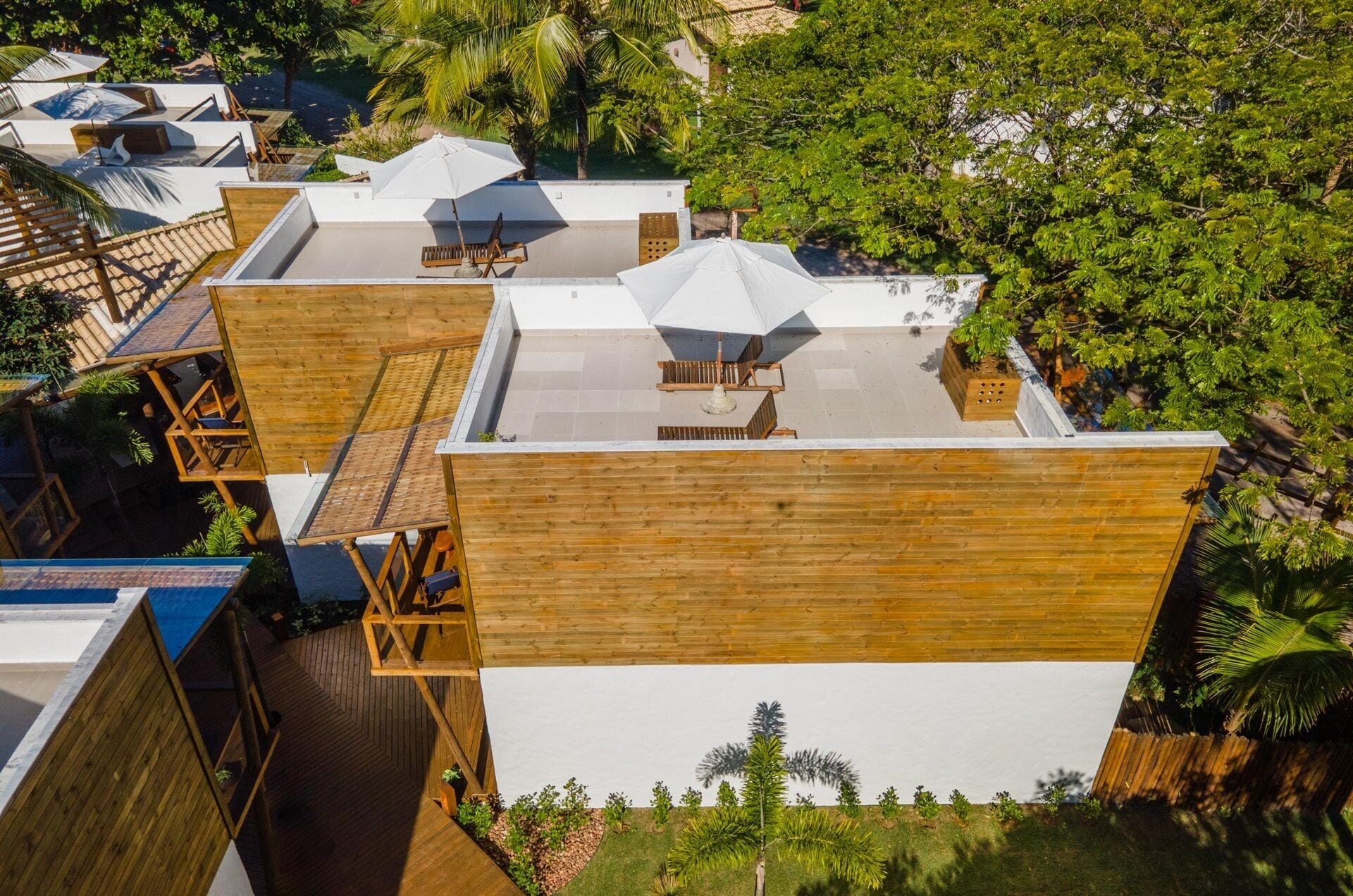A rooftop terrace with wooden deck, lounge chairs, and umbrellas.