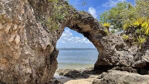 A natural rock formation with a tunnel-like opening leading to a beach. - Mayim Villa (Maraú)
