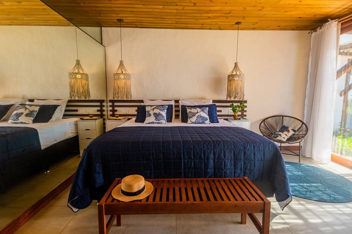 A bedroom with a large bed, two bedside tables, a wooden bench, and a chair.