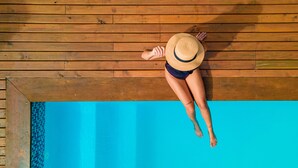 A person lying on a wooden deck above a swimming pool. - Mayim Villa (Maraú)
