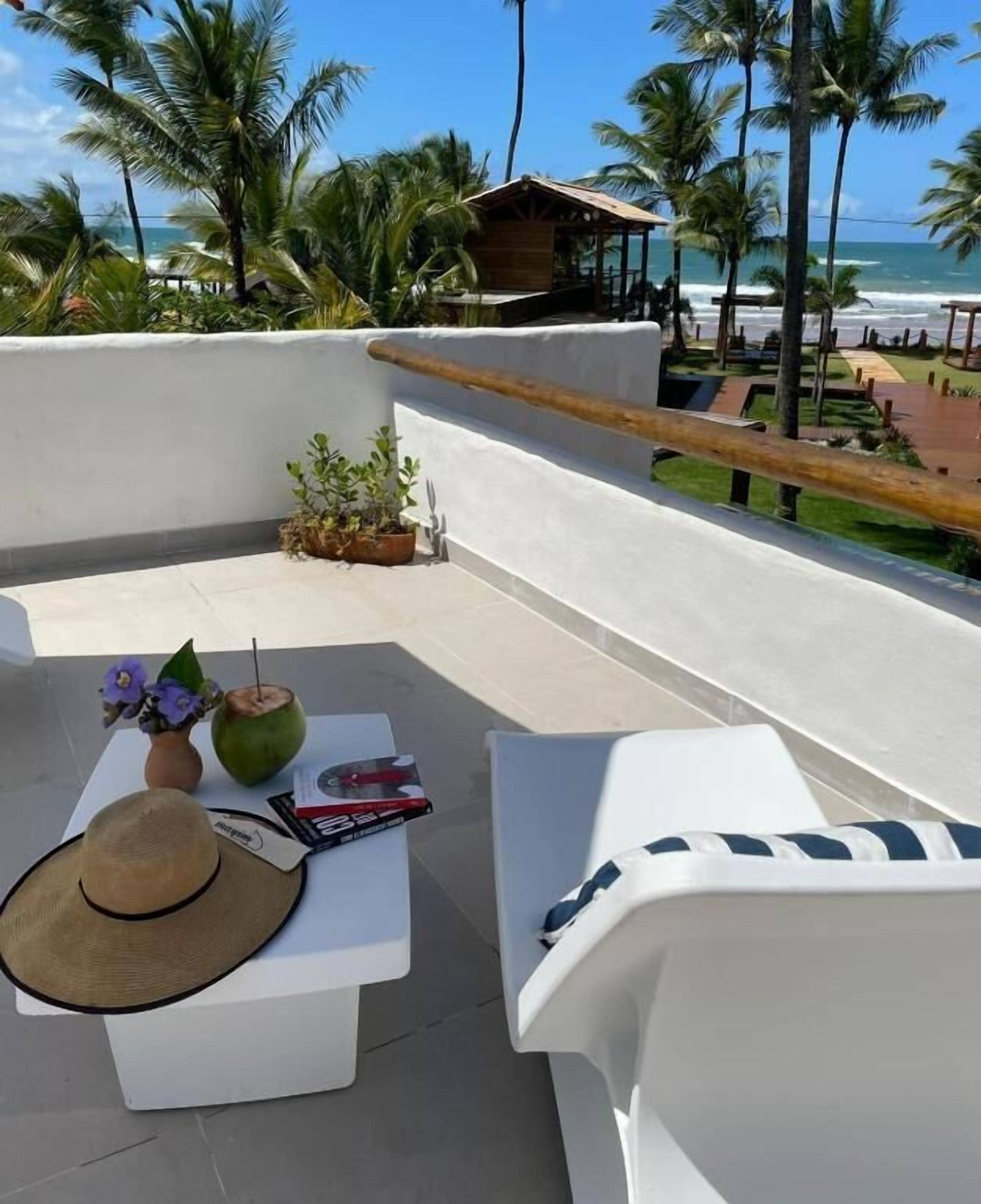 A rooftop terrace with a white table, a hat, a plant, and a book.