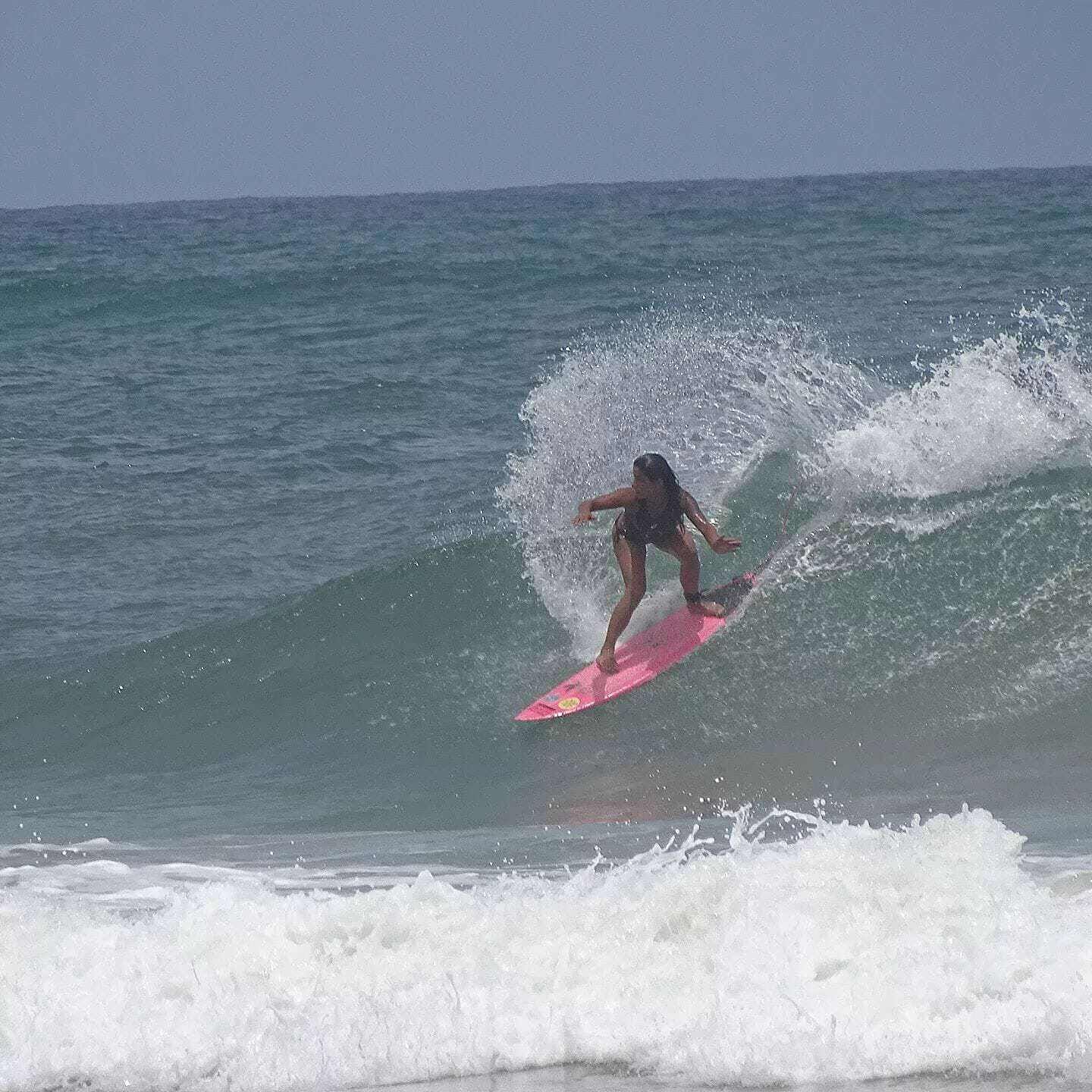 Una persona surfeando en una tabla rosa en el océano.