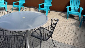 An outdoor patio with a round table and four turquoise chairs, surrounded by a wooden deck. - The Asbury House Guest Rentals (Moscow)
