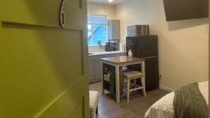 A compact kitchen with a microwave, refrigerator, and a small dining table with a chair. - The Asbury House Guest Rentals (Moscow)