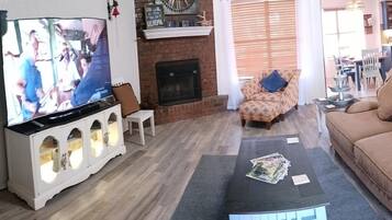 Una sala de estar con televisión, chimenea, sofá y mesa de centro.