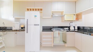 A compact kitchen with a refrigerator, stove, microwave, and cabinets. - GB67 Ótimo Apto 2 Suítes - Guarajuba (Camaçari)