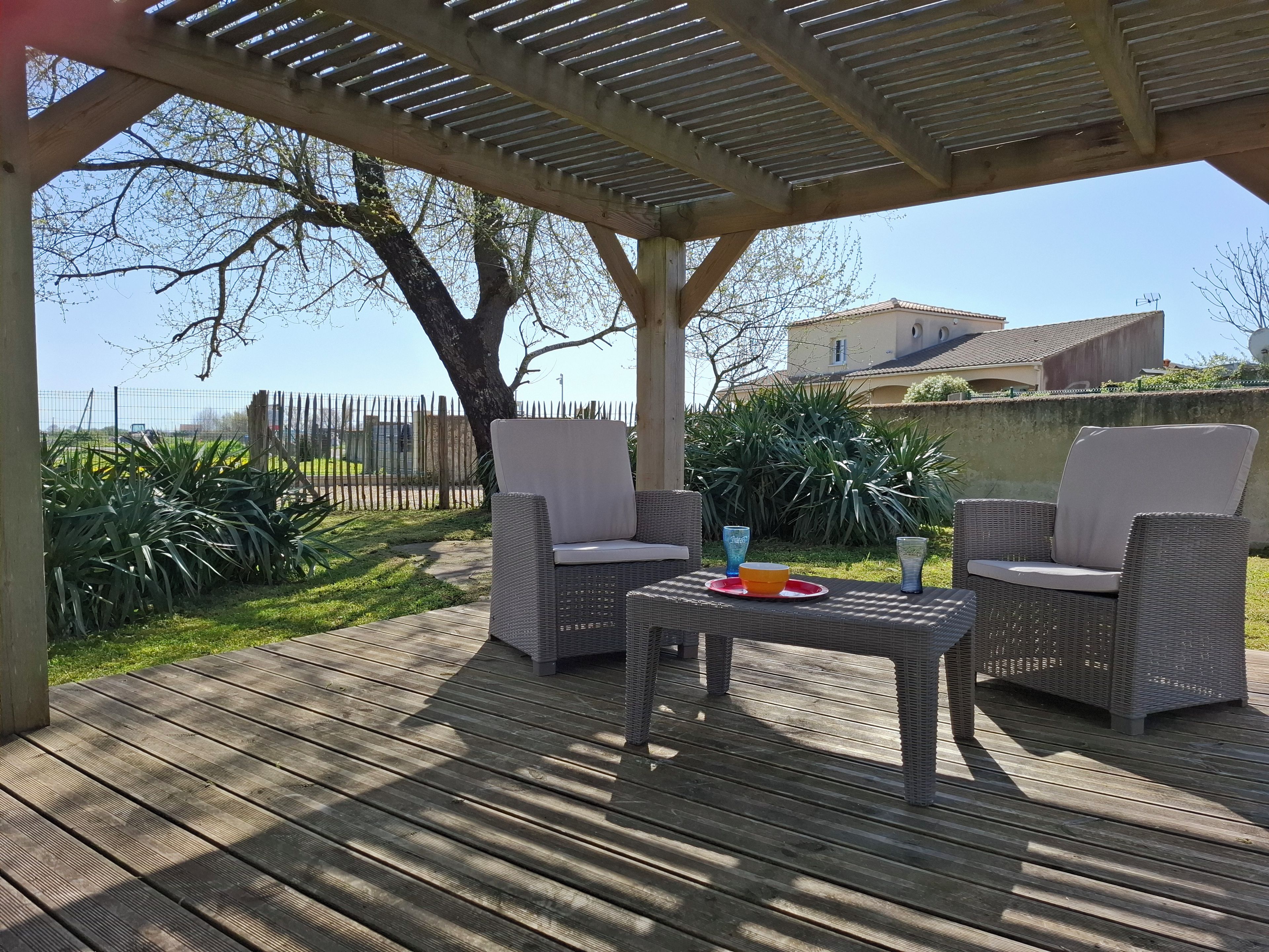 Une terrasse extérieure avec des meubles en osier, une table et un saladier.