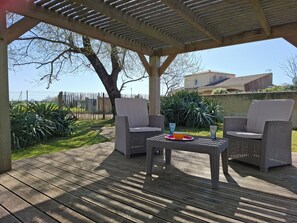 An outdoor patio with wicker furniture, a table, and a bowl. - Maison à 50m de L'océan (Yves)