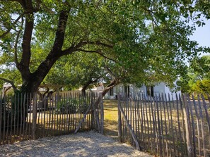 A fenced outdoor area with a gravel path leading to a white building with a porch. - Maison à 50m de L'océan (Yves)