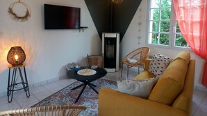 A cozy living room with a sofa, a table, a TV, and a fireplace. - Maison à 50m de L'océan (Yves)