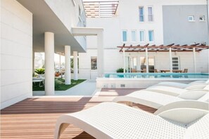 A modern outdoor pool area with lounge chairs and a pergola.