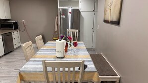 A dining area with a striped tablecloth, wooden chairs, a vase with flowers, and a refrigerator in the background. - Beautiful house on farm, Nature lover's paradise (Rosemont)