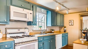 Una cocina con gabinetes color turquesa, un microondas blanco, una estufa y un lavamanos.