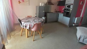 Een ruimtelijk ingerichte leefruimte met een eethoek, kitchenette en een bed.