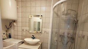 Een badkamer met een wit wastafelmeubel, spiegel en douchecabine.