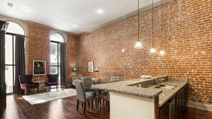 A kitchen with a brick wall, wooden flooring, and a granite countertop.