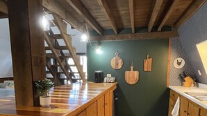 A kitchen with wooden cabinets, a countertop, and a green wall with hanging wooden utensils.
