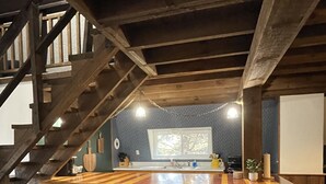 A kitchen with a wooden island, bar stools, and a staircase.