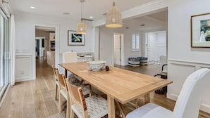 Un comedor con una mesa de madera, sillas y lámparas colgantes.