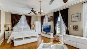 A bedroom with a bed, a TV, a ceiling fan, and a window with curtains. - Casa del Mundo 2bd 3.5ba With Private Pool (West Palm Beach)