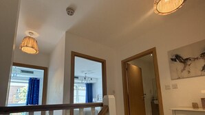 En trappa leder upp till en liten plattform med utsikt över en gata och en byggnad. Därifrån finns en dörr som leder in i ett annat rum med en spegel och en byrå.