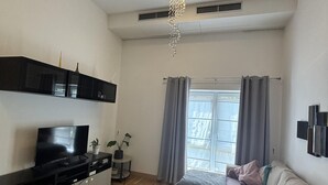 Ett modernt vardagsrum med en platt-TV, en soffa, ett soffbord och en dekorativ kristallkrona.