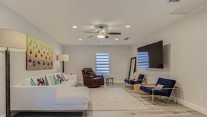 A spacious living room with a white sofa, two recliners, a coffee table, a floor lamp, and a ceiling fan. - Alhambra Place 4 BR 3 BA Pool Vacation Home (West Palm Beach)