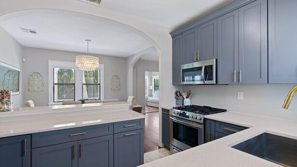 A modern kitchen with grey cabinets, a stainless steel range, and a large island with a sink. - Casa Sunshine NEW (West Palm Beach)