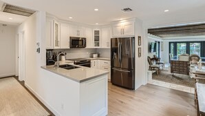 A modern kitchen with white cabinetry, stainless steel appliances, and a large island. - Cortez Bungalow, 3 Bd 2 Ba, Private Pool (West Palm Beach)