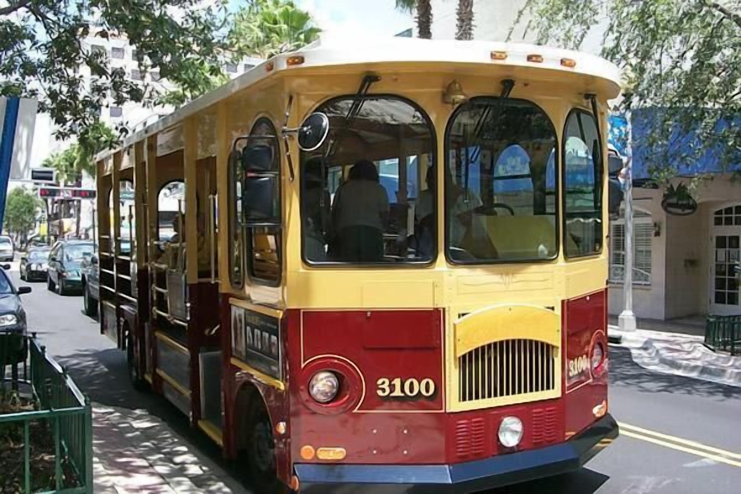 A vintage yellow and red bus with the number 3100 on the front, parked on a city street.