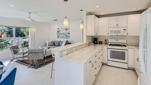 A modern kitchen with white cabinetry, a central island, and a built-in microwave.