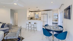 A modern kitchen with white cabinets, a central island, and blue bar stools.