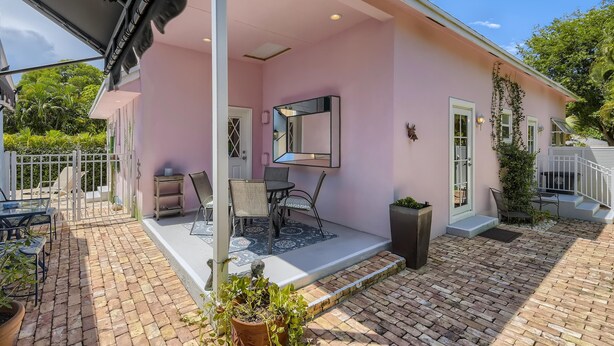 A pink building with a covered patio, outdoor seating, and a large mirror. - Nini's Cottage 4bd 3ba Vacation Rental (West Palm Beach)