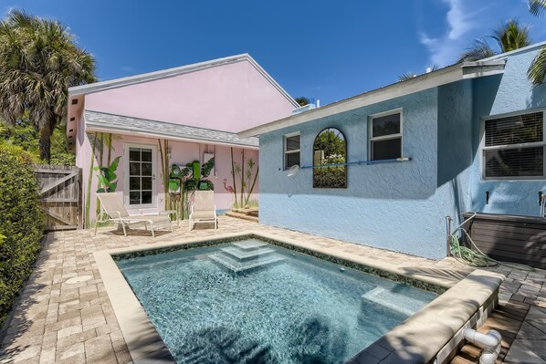 A house with a swimming pool, a patio, and a covered area with chairs.