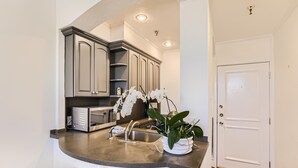 A kitchen with a curved countertop, built-in cabinets, a microwave, and a sink. - Palm Beach Hotel (Palm Beach)