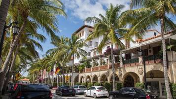 A hotel with a courtyard, palm trees, and a street view.