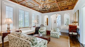 A spacious living room with a high wooden ceiling, large windows with blinds, and a chandelier. - Villa Blanca 4bd 3.5ba Private Pool and Parking (West Palm Beach)