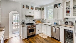 A spacious kitchen with white cabinetry, a marble backsplash, and a built-in oven. - Villa Blanca 4bd 3.5ba Private Pool and Parking (West Palm Beach)