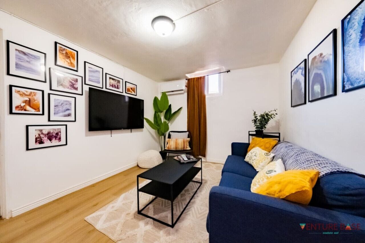 A modern living room with a blue sofa, a black coffee table, and framed artwork on the walls.