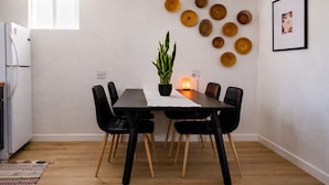 Uma área de refeições com uma mesa, cadeiras, um vaso de planta, uma luminária de sal e decoração nas paredes.