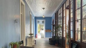 Un pasillo con baldosas de diseño, un sofá amarillo y un mueble de madera con plantas.