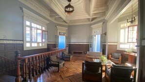 Una habitación espaciosa con piso de parquet de madera, una escalera con barandilla de madera y un candelabro.