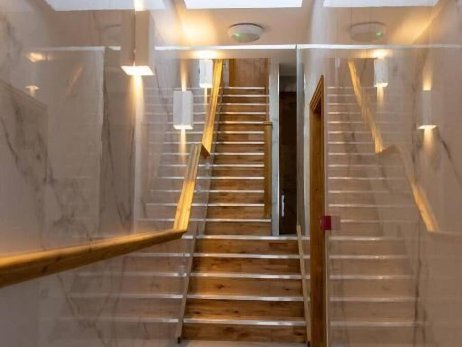 A modern interior with a marble staircase, wooden handrails, and recessed lighting.