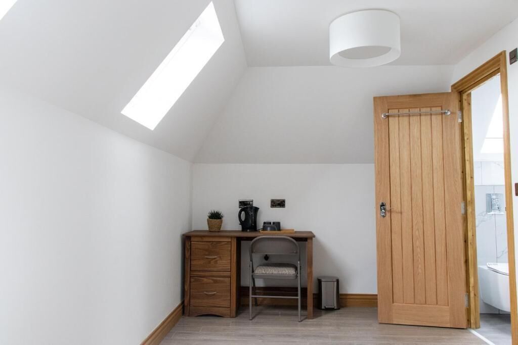 Una habitación pequeña y luminosa, con un escritorio, una silla y una puerta de madera.
