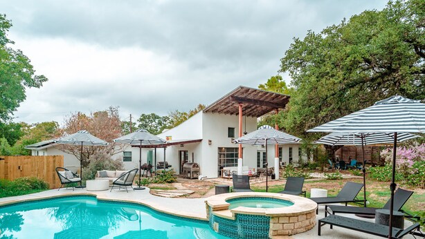 Un jardin avec une piscine, des chaises longues et des parasols.