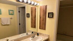 Une salle de bain avec un double lavabo, des meubles en bois, un grand miroir et un espace douche.