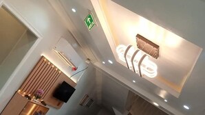 Un hall d’hôtel moderne avec un comptoir d’accueil, un escalier et un luminaire au plafond.